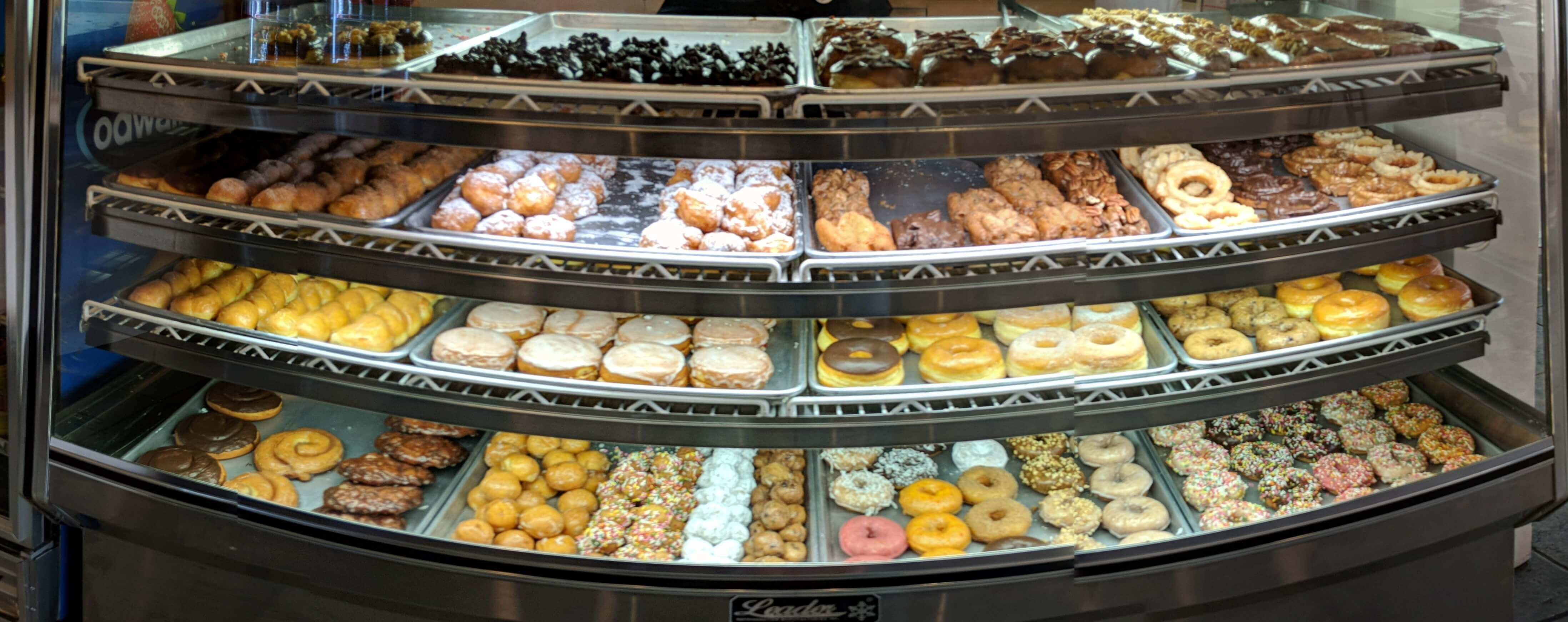 A glass display case filled with a variety of glazed donuts.