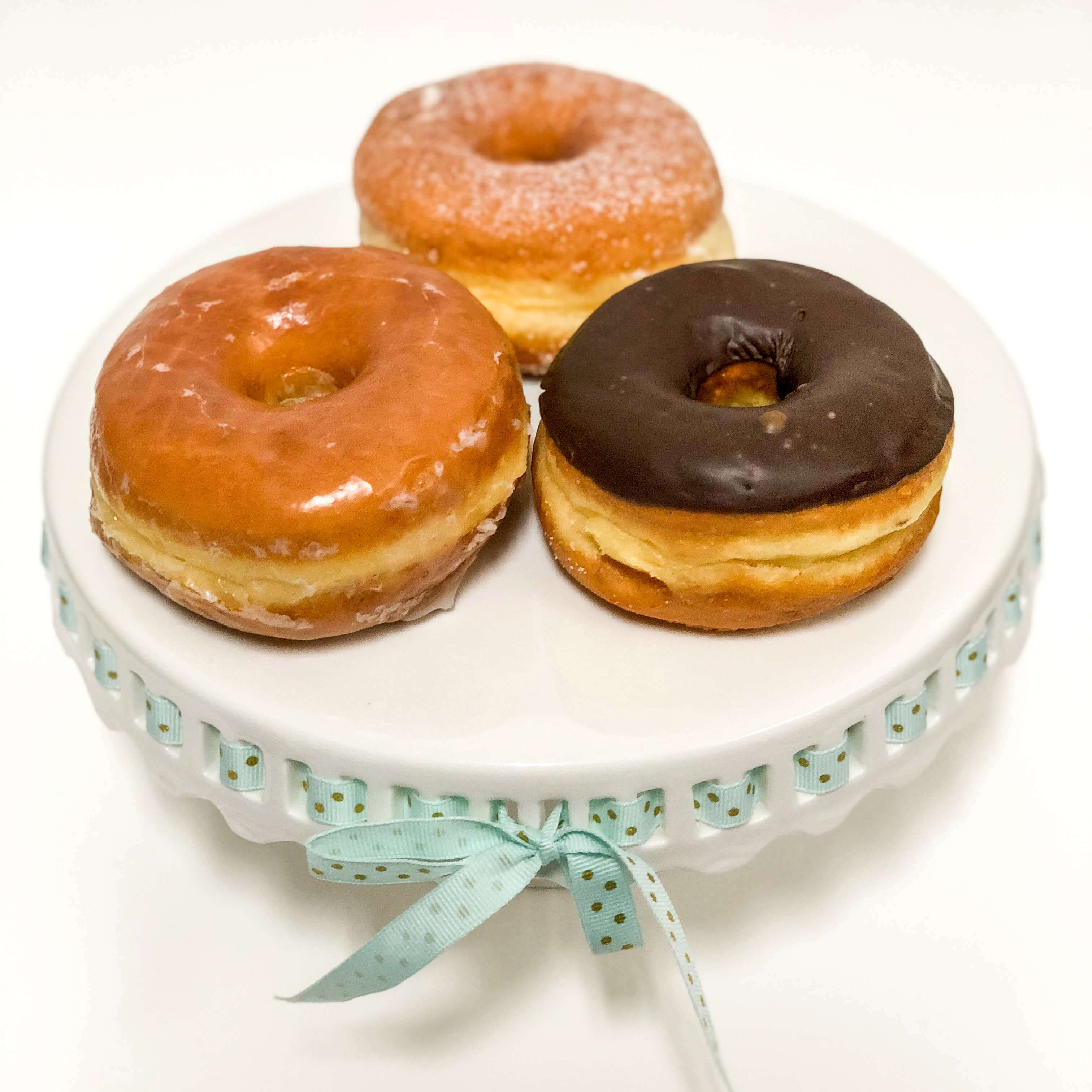 Three raised donuts atop a display stand.